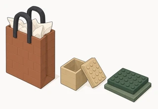 A brown gift bag with black handles and white tissue paper, a small tan box with its lid off, and a flat dark-green block on a lighter green base.