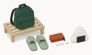 A green backpack on a low slatted luggage rack, with a pair of sage slippers, a terracotta coin purse with three plain coins, and a triangular rice ball wrapped in a dark band.