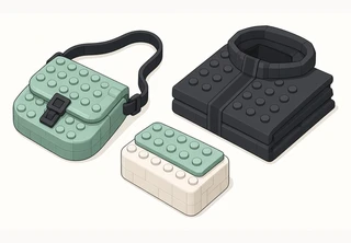 A small sage sling bag with a black strap and buckle, next to a folded charcoal jacket and an off-white box with a sage lid.